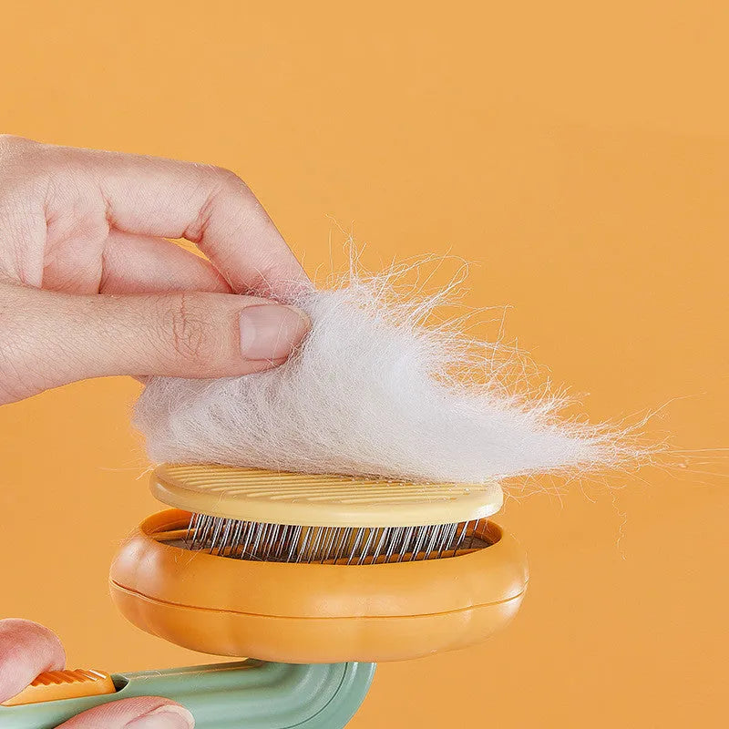 Pumpkin-coloured self-cleaning pet grooming brush with stainless steel needles for cats and dogs.