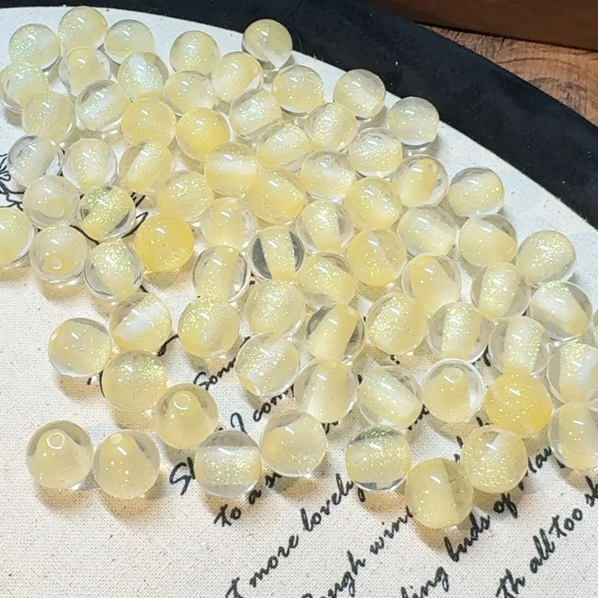 16mm round plastic scattered beads with glittering cat's eye effect in champagne colour, on a white background.
