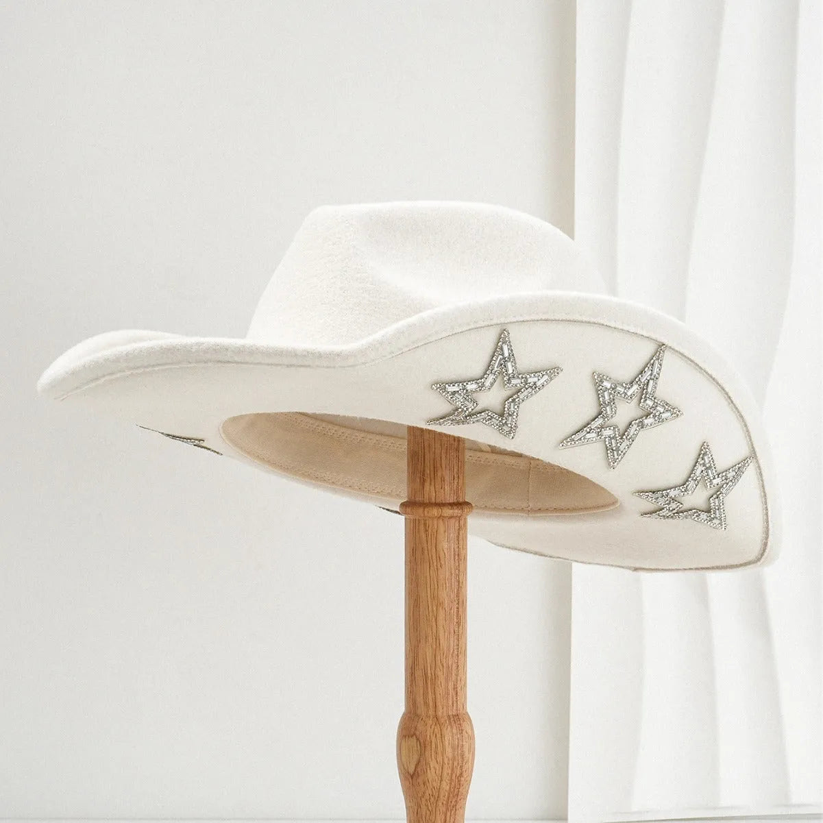 Beige woolen felt western denim top hat with a conical crown and a hexagonal star decoration on the front.