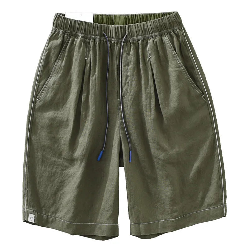 Man wearing loose fit green linen shorts with a straight leg and drawstring waist for casual summer wear.