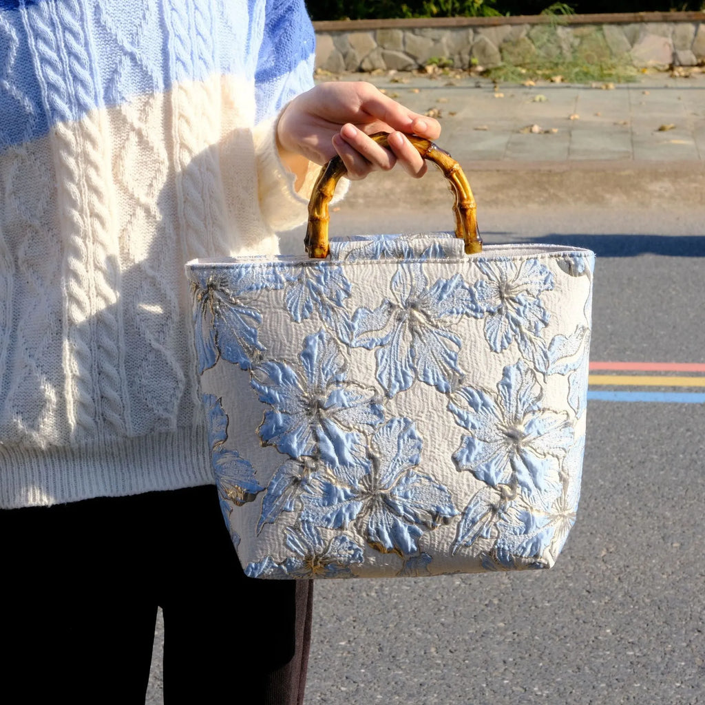 Light blue canvas shoulder bag with gold floral pattern showing 30x30x10 cm dimensions and double straps