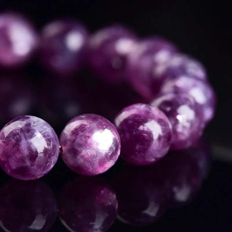 Geometric purple and pink polished crystal bracelet on a wrist, showing single strand of beads.