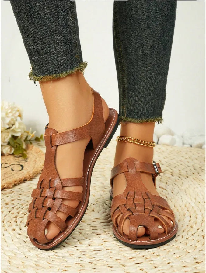 Dark brown women's Roman sandals with woven PU upper and buckle closure on a rubber sole.