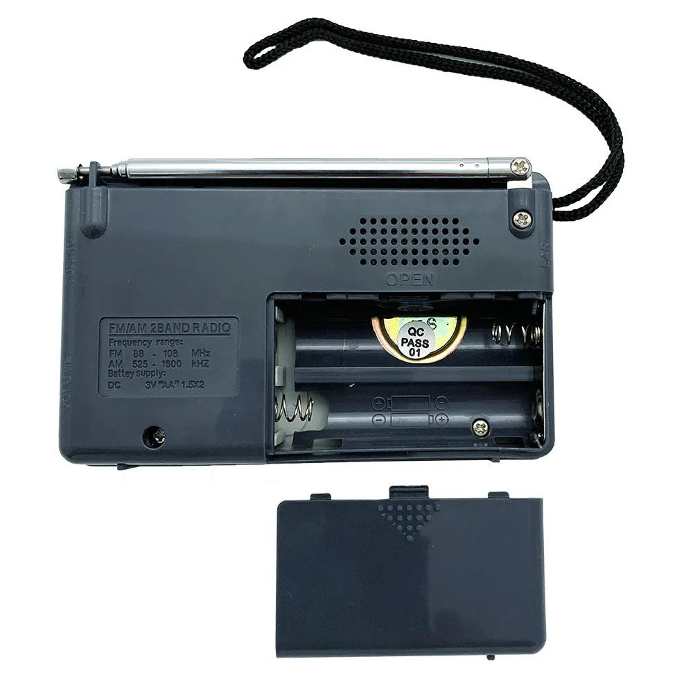 Portable silver grey FM AM radio on table, compact ABS body with built-in speaker and dial controls