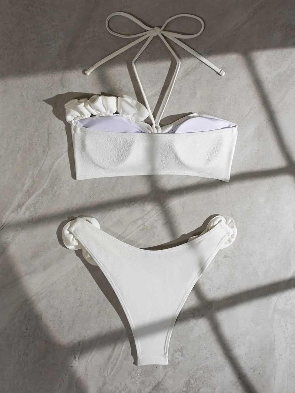 White halter neck bikini set with lace-up back and three-dimensional floral pattern on briefs.