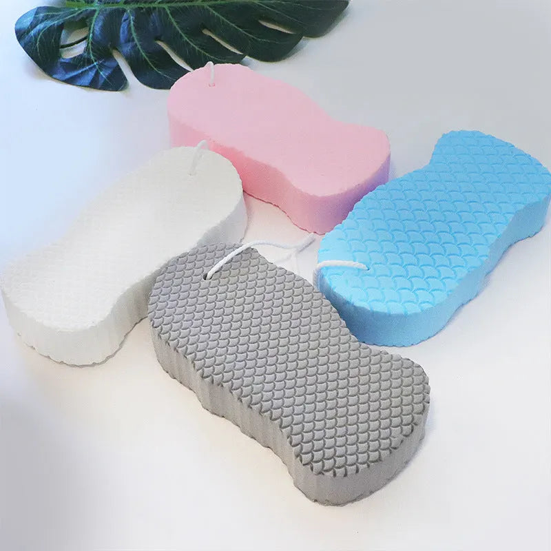 White 3D fish scale pattern bath sponge with hang loop on a bathroom background.