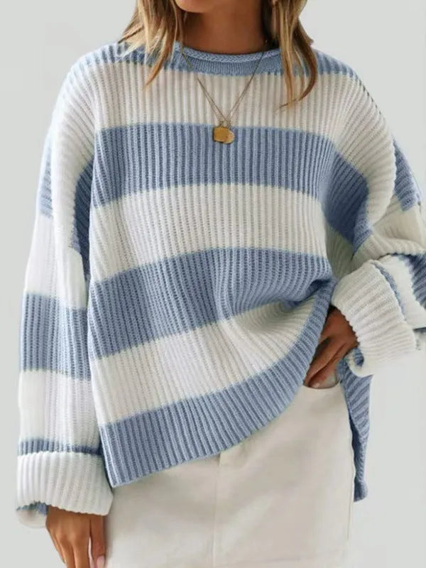 Woman wearing a loose striped sweater with long bell sleeves and white crocheted flower details on the front.