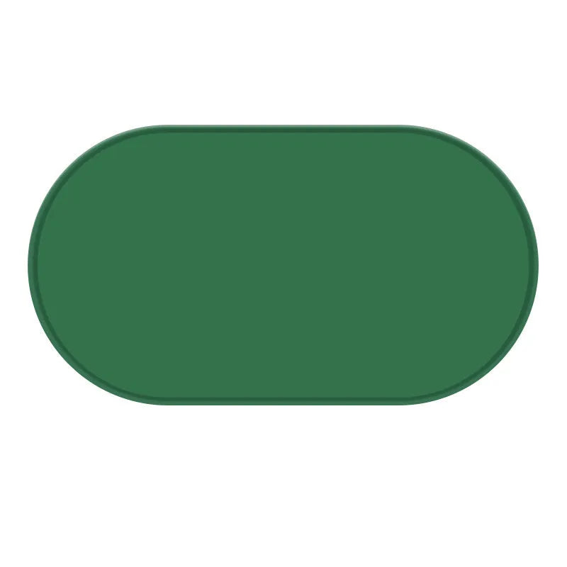 Green silicone cat feeding mat with raised edges containing dry kibble, placed on a wooden floor.