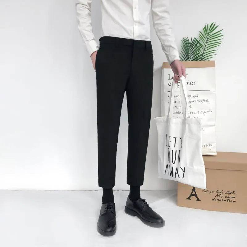 Man wearing black straight-leg cotton trousers with a drawstring waist, styled casually.
