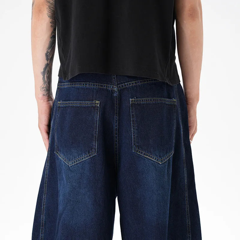 Dark blue washed distressed denim wide leg machete jeans laid flat, showing the wide leg cut and textured finish.