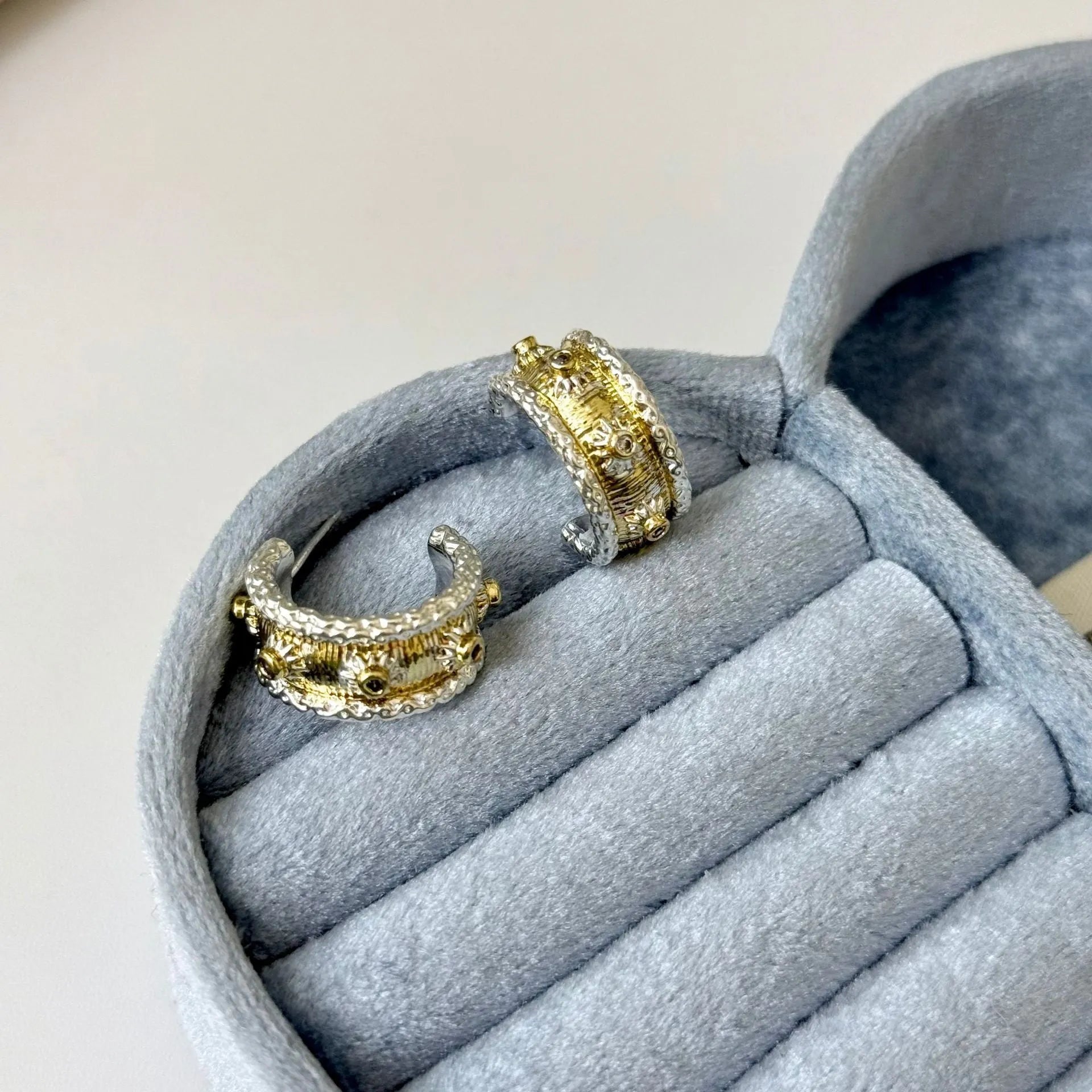 Gold and silver C-shaped brushed ring earrings on display, copper with 925 silver needles