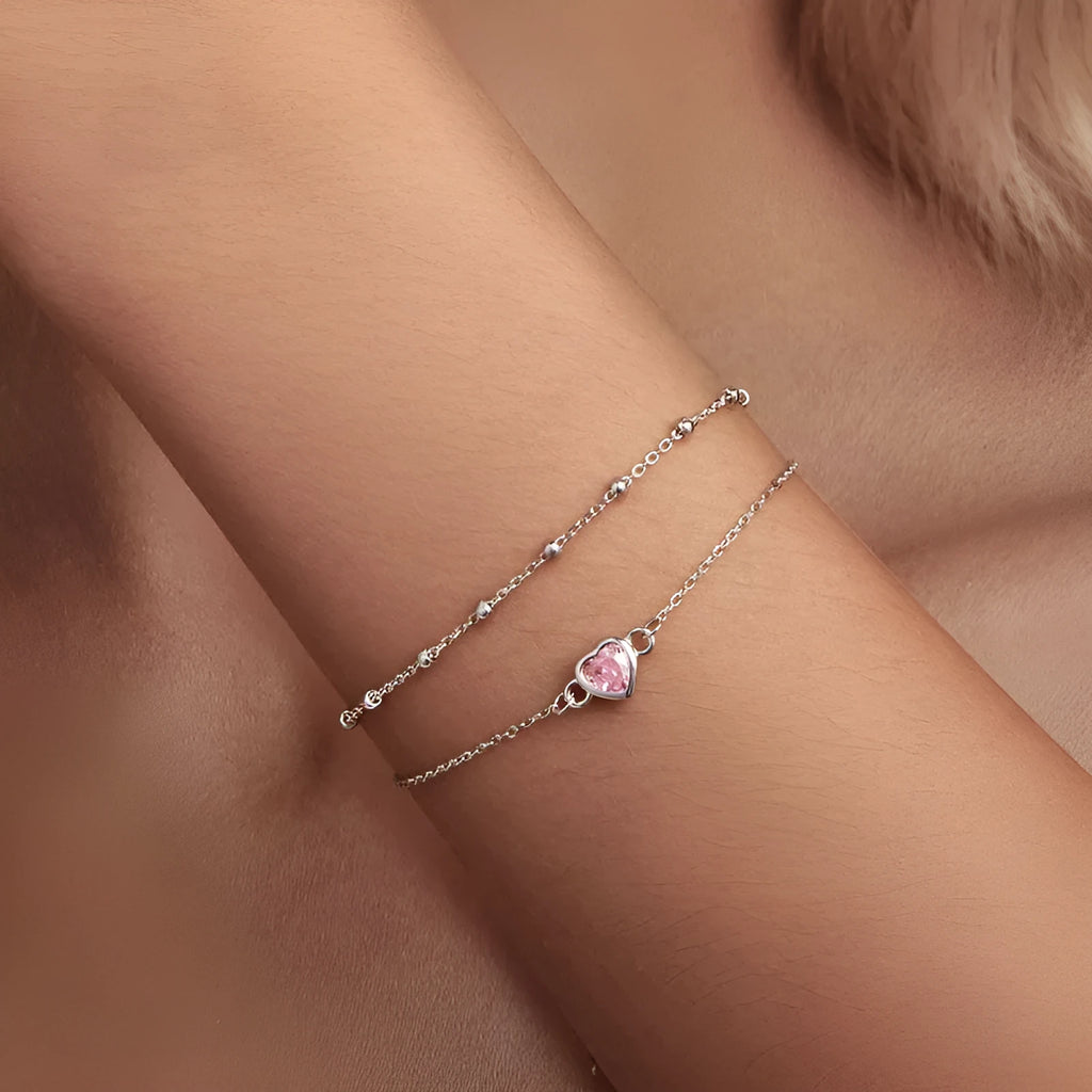 Close-up of a sweet girlish style sterling silver bracelet with a small heart pendant on an adjustable chain.
