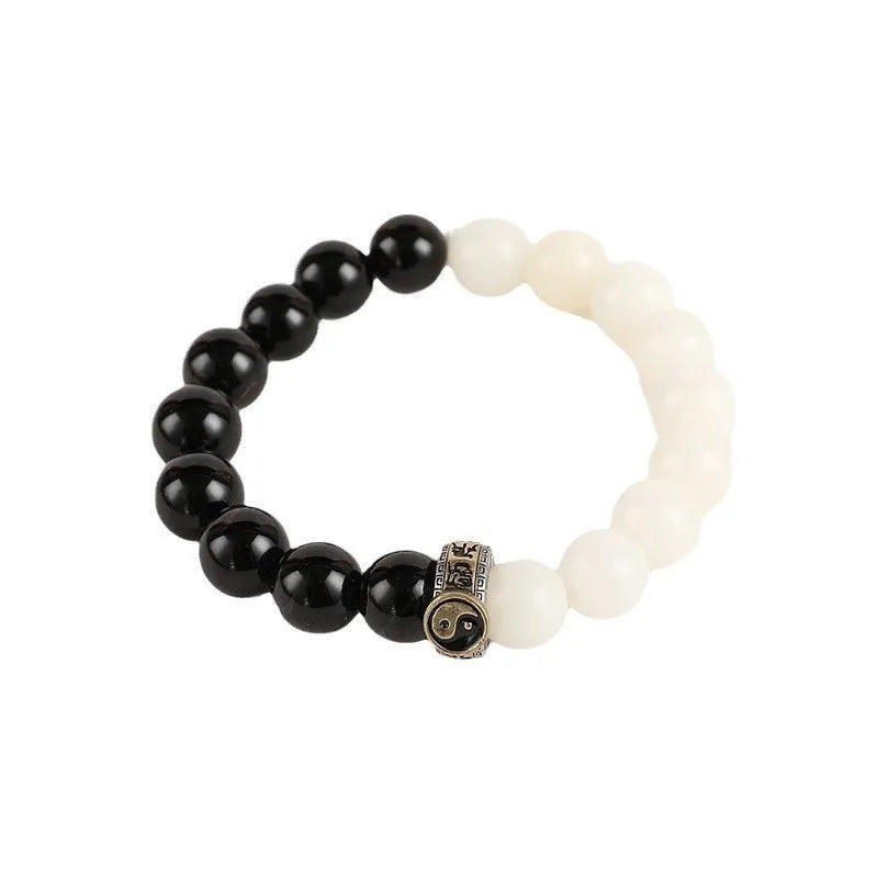 Black and white obsidian Tai Chi bracelet with geometric beads showing mantra inscriptions.