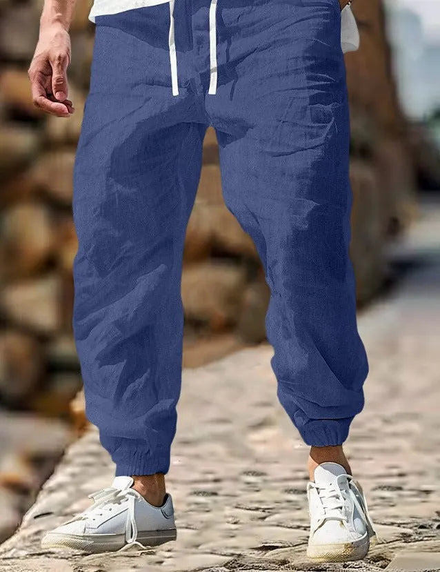 Men's straight-leg cotton trousers with an elastic waistband in apricot colour on a hanger.