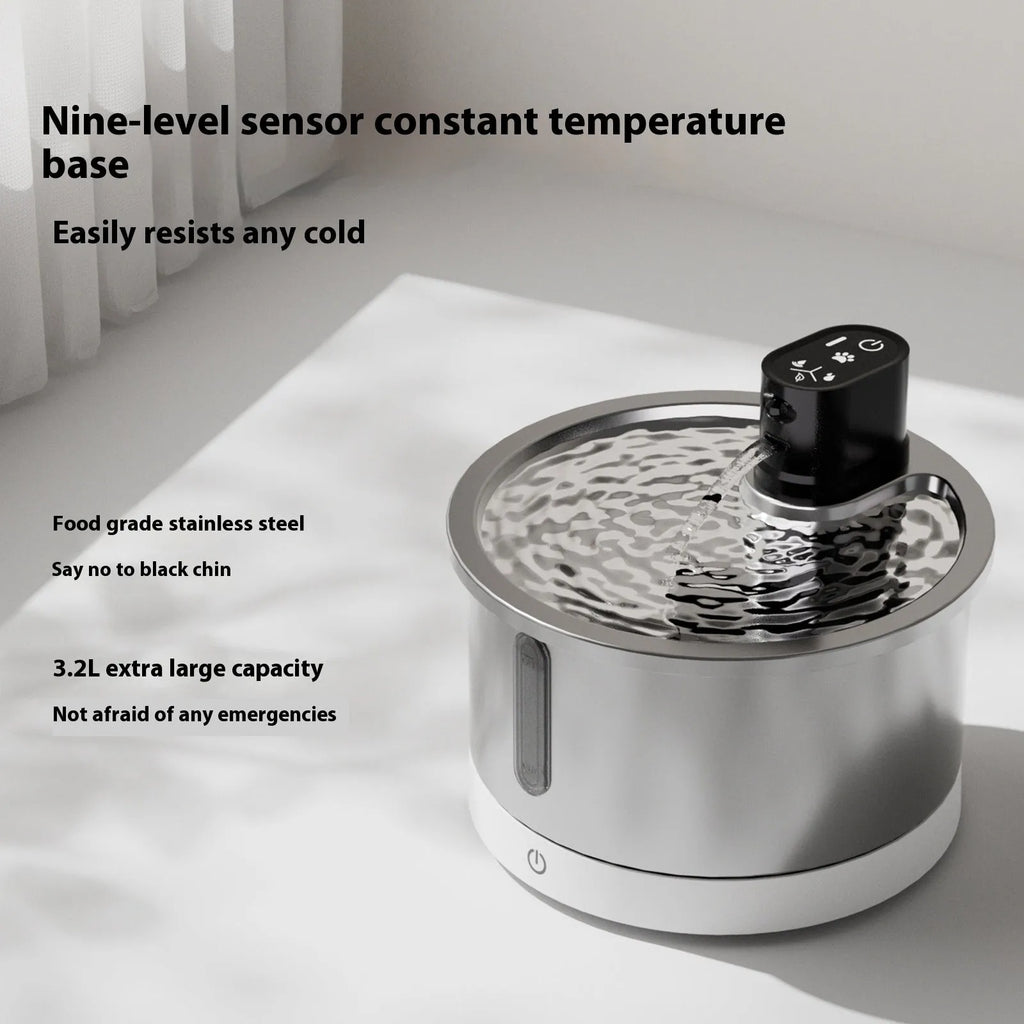Stainless steel cat water fountain with heating base on a table.