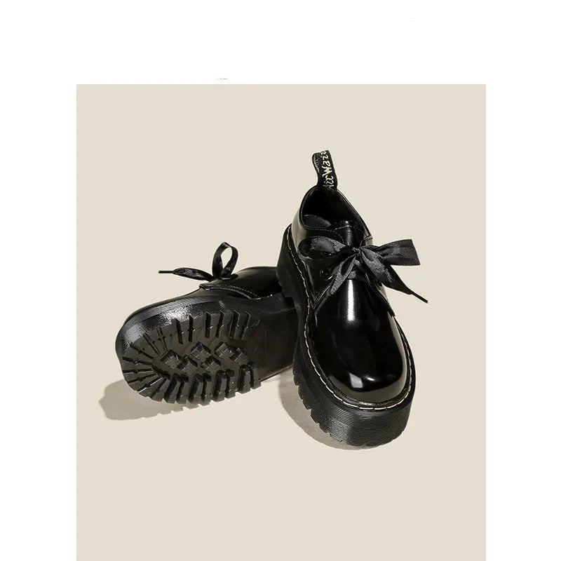 White and black women's thick soled shoes with ribbon and cross straps and laced closure.