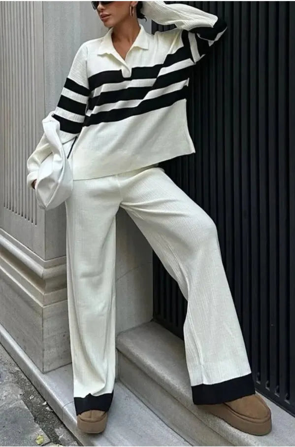 Women's black and white striped knitted polo shirt with long sleeves paired with matching trousers.