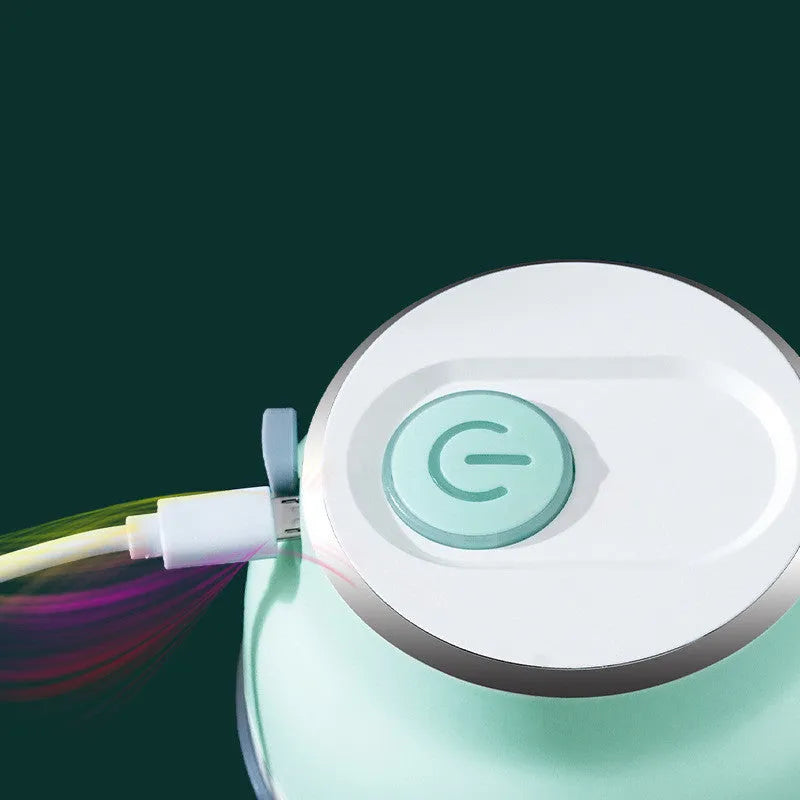 Portable electric mini garlic cutter with green body, transparent cup, and stainless steel blade on table