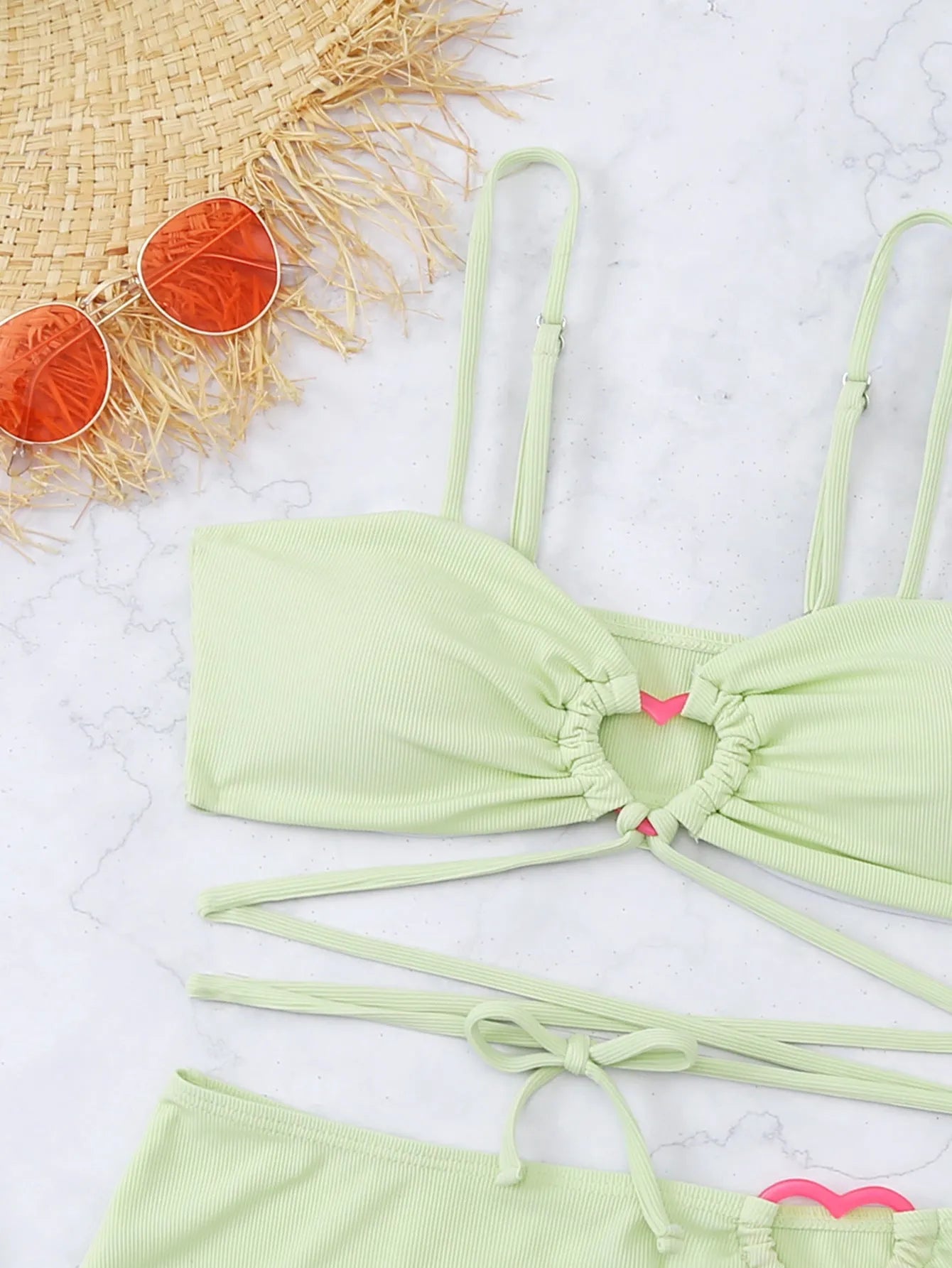 Three-piece women's bikini swimsuit with lace heart design in fruit green colour, shown on mannequin
