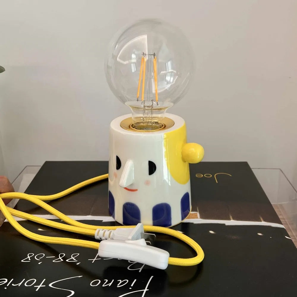 Off-white handmade ceramic table lamp with a rounded shape on a wooden surface.