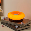 Donut touch table lamp rechargeable with three colour settings, shown in custard, green, orange, or pink.