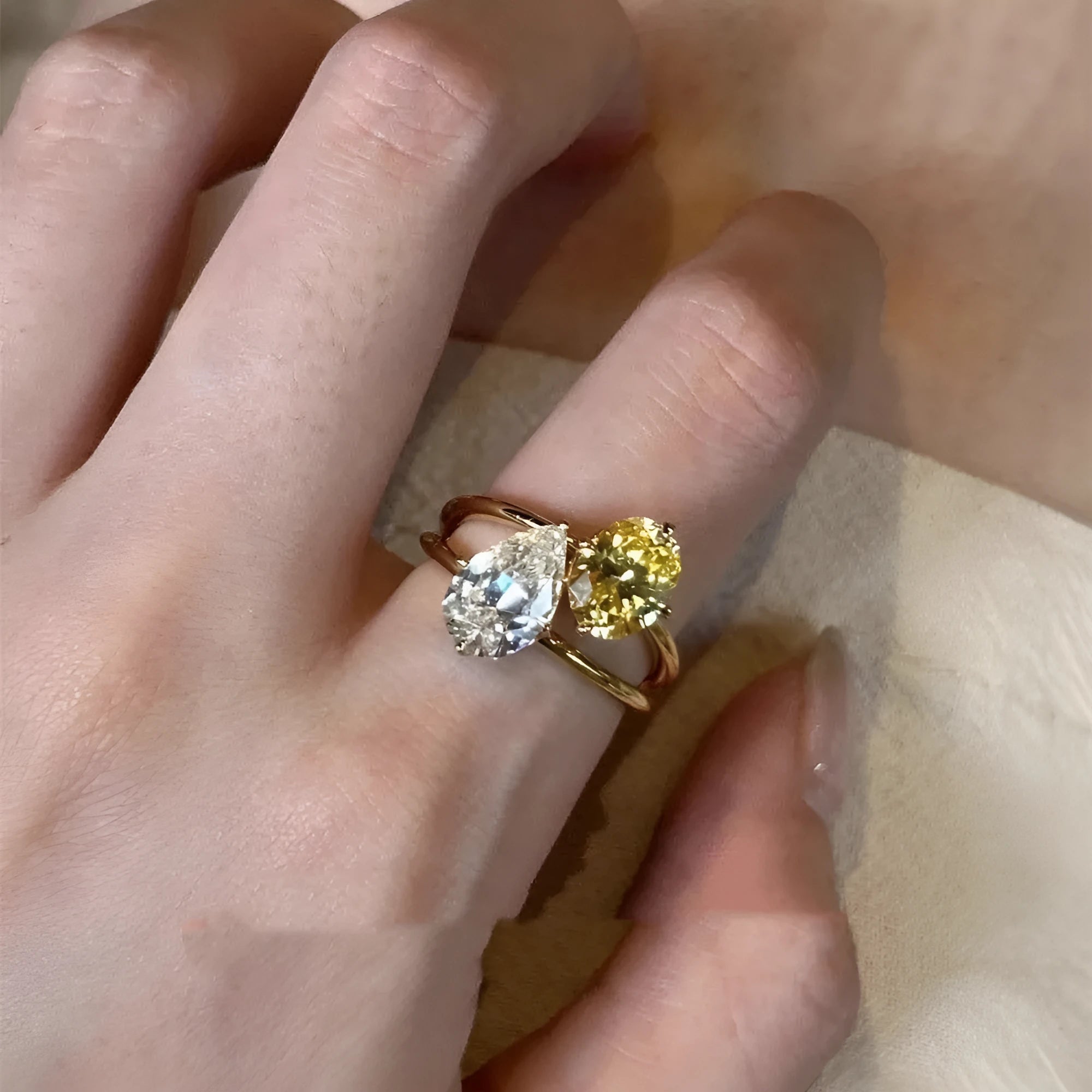 Geometric open copper ring with two sparkling zircon stones in a water drop setting on a model's finger.