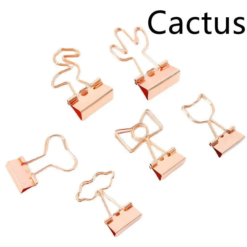 Gold metal alloy paper clip with decorative bow shape top on white background.