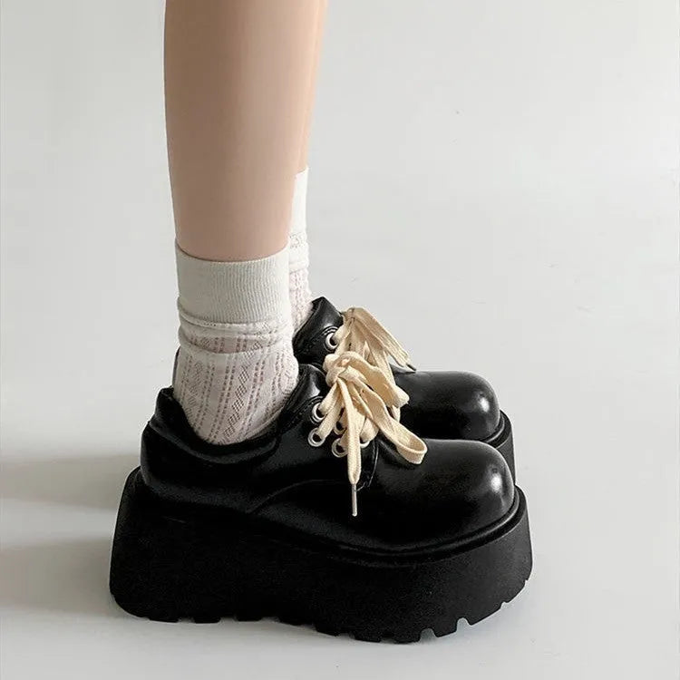 Matte black women's lace-up platform shoes with a thick sole and chunky English muffin heel.