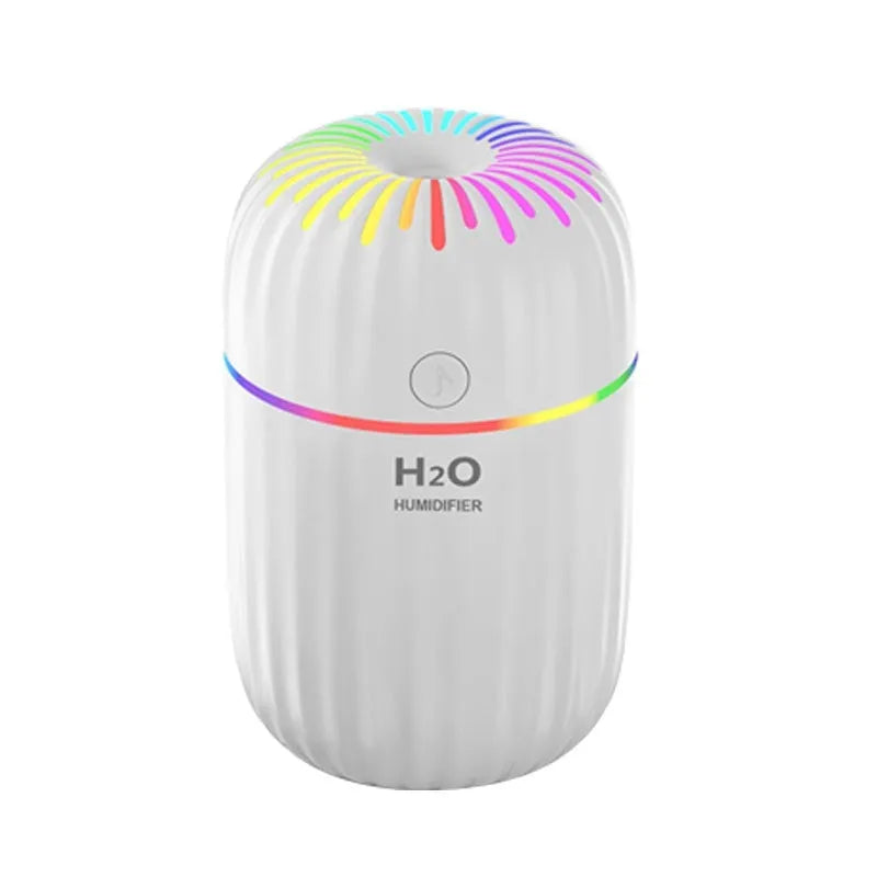 Compact white USB mini humidifier with water tank on a desk next to a laptop.