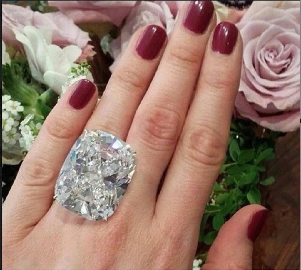 Simple white gold colour ring with an inlaid square diamond geometric design, shown on a model's hand.