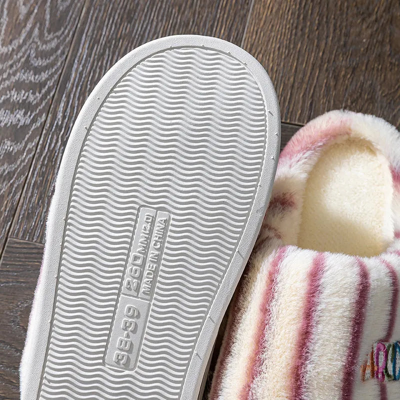 A pair of colourful vertically striped cotton flip flop slippers for adults on a plain background.