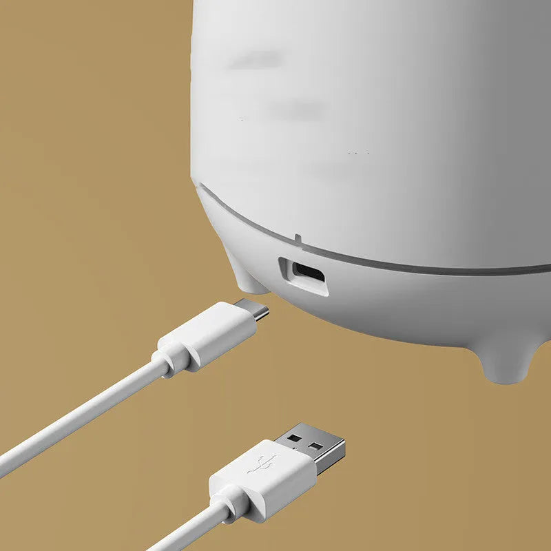 White volcano-shaped ultrasonic humidifier with USB cable on a table