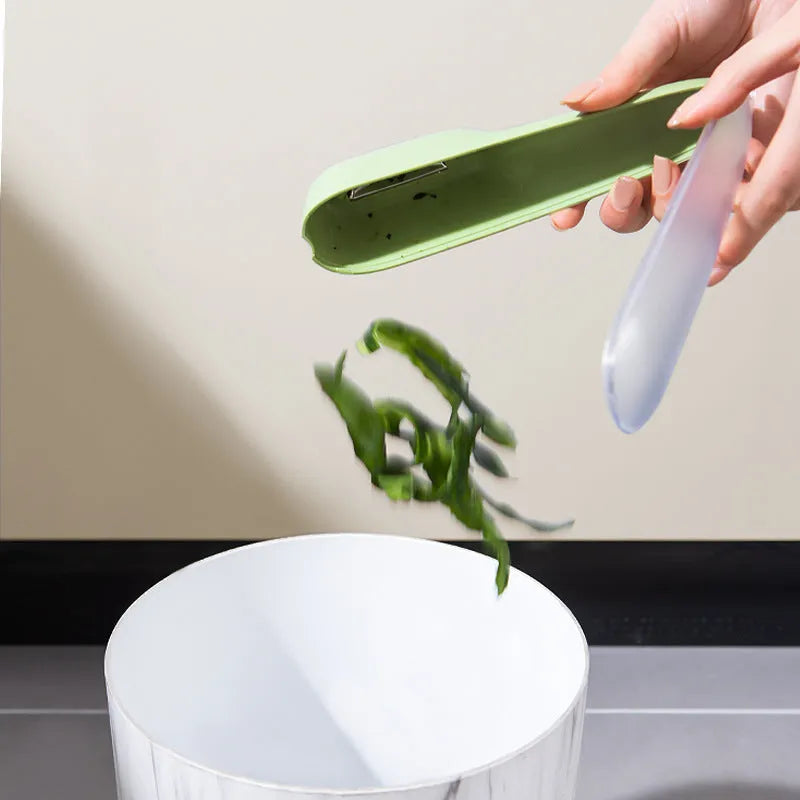 Dark green kitchen peeler with storage tube showing stainless steel blade and hanging hole