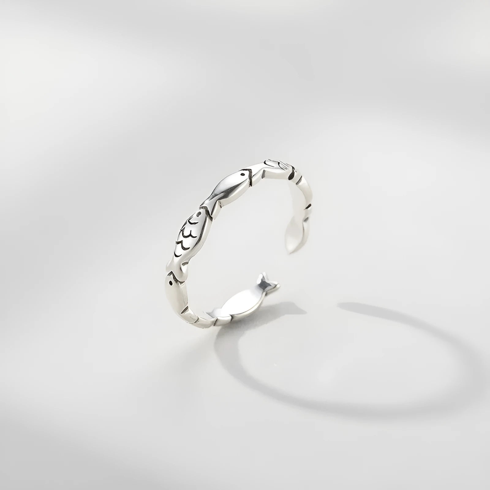 Close-up of a women's adjustable sterling silver ring with a vintage fish design on a finger.