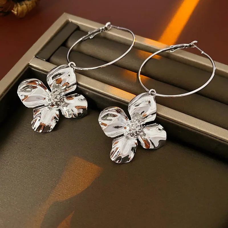 A pair of vintage-style geometric flower earrings with silver needle detailing, shown in gold and silver colour options.