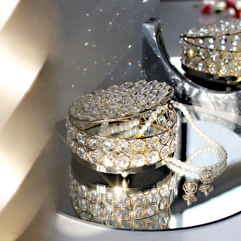 Transparent crystal glass jewelry storage box with a French gold-coloured metal frame on a table.