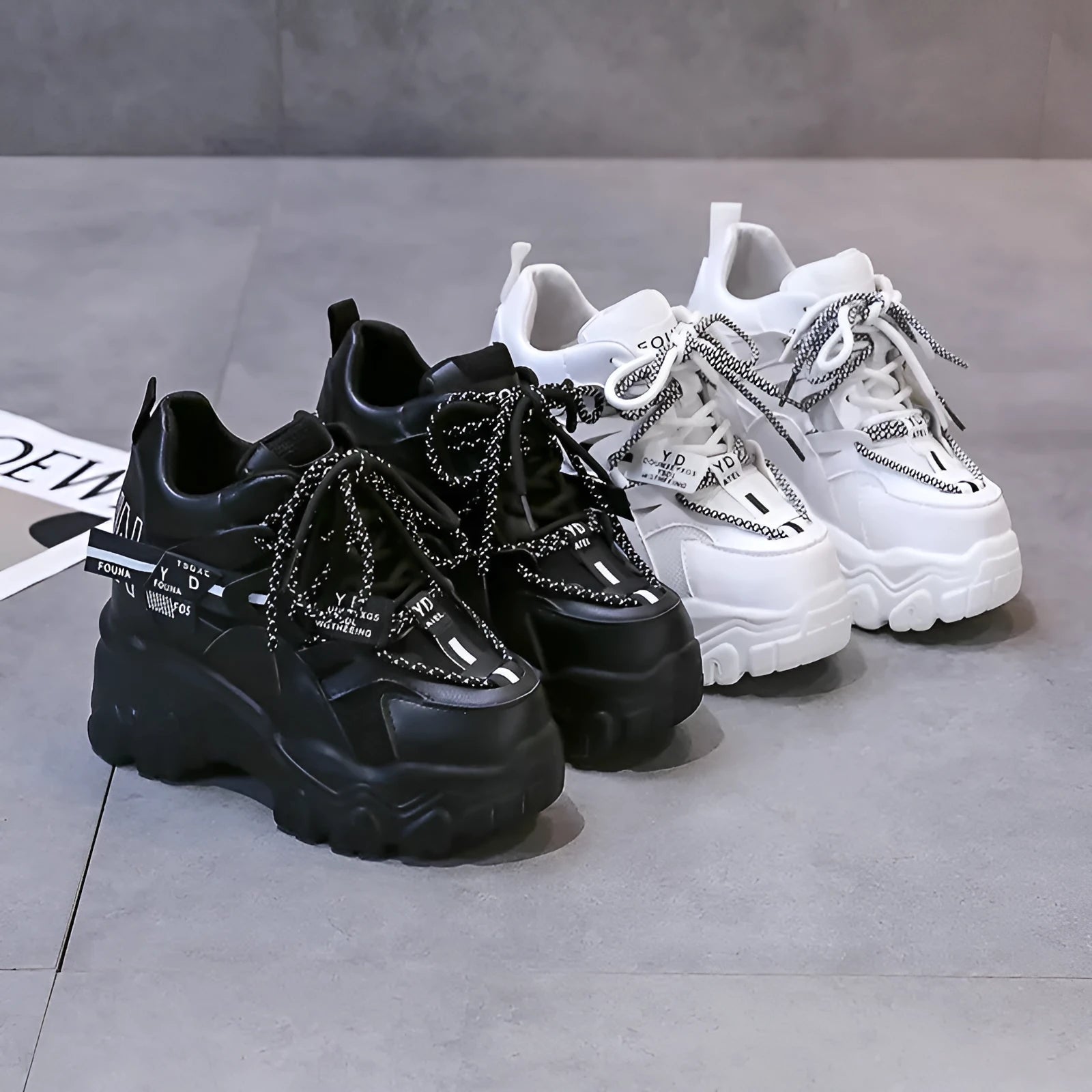 White women's low-top platform sports trainers with mesh panels and a black cross-strap on a rubber sole.