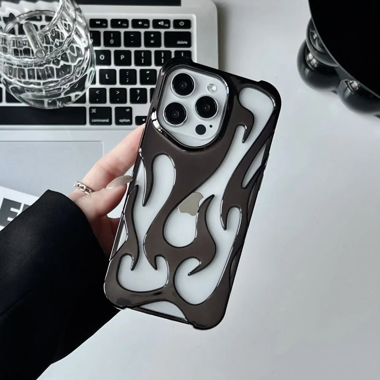 Electroplated hollow flame pattern mobile phone case for iPhone on a dark background, showing silver metallic finish.