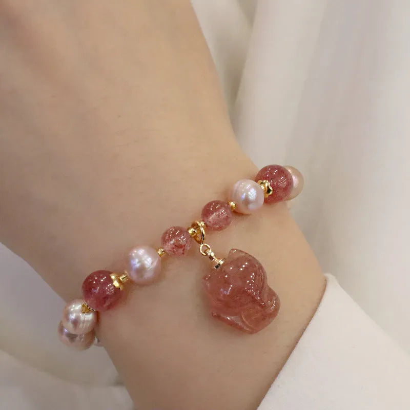 Light pink women's bracelet with freshwater pearls, strawberry quartz beads, and a silver fox charm on a white background.