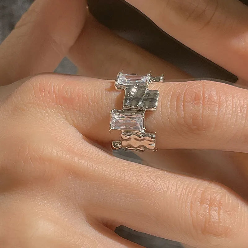 Silver plated open ring with cross design and zircon crystals.