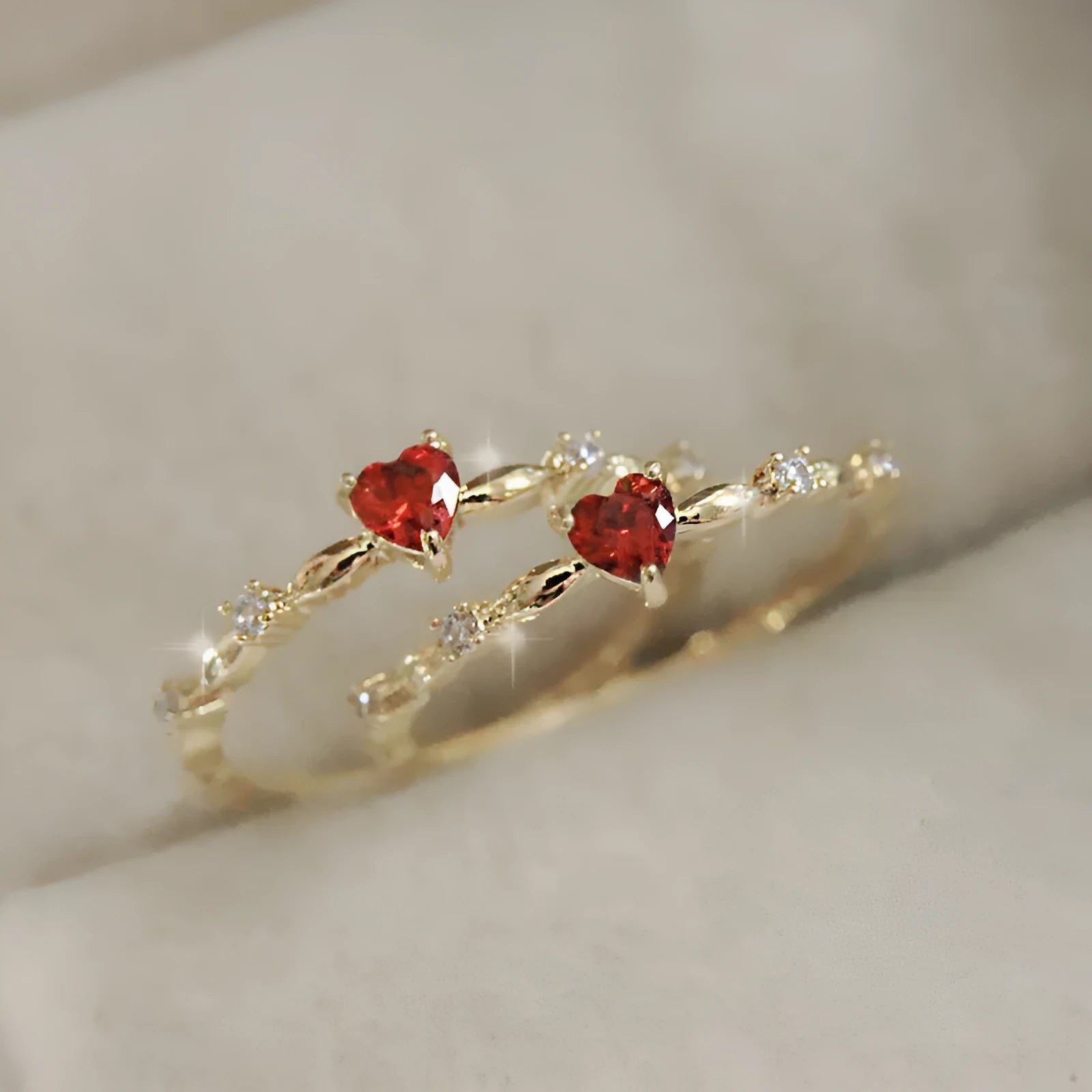Copper fashion ring with peach heart zircon detail in gold or silver electroplating, shown on a finger.