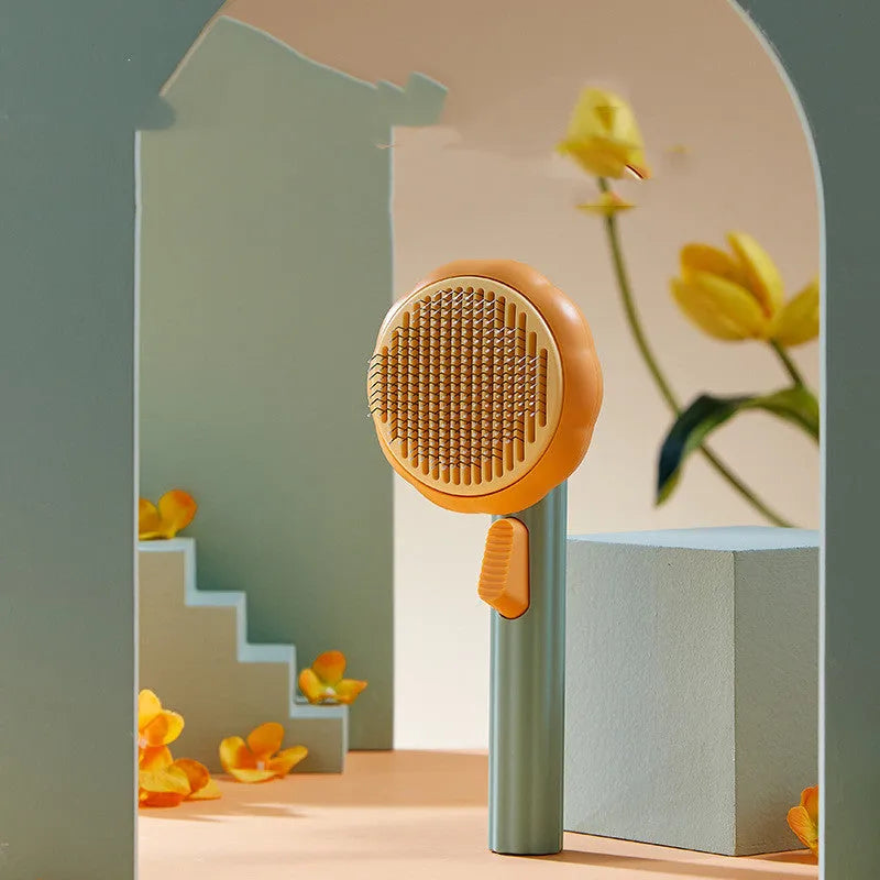 Pumpkin-coloured self-cleaning pet grooming brush with stainless steel needles for cats and dogs.