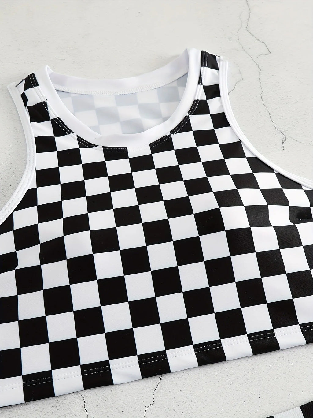 Women's backless one-piece swimsuit with black and white chessboard pattern and sporty suspender straps.