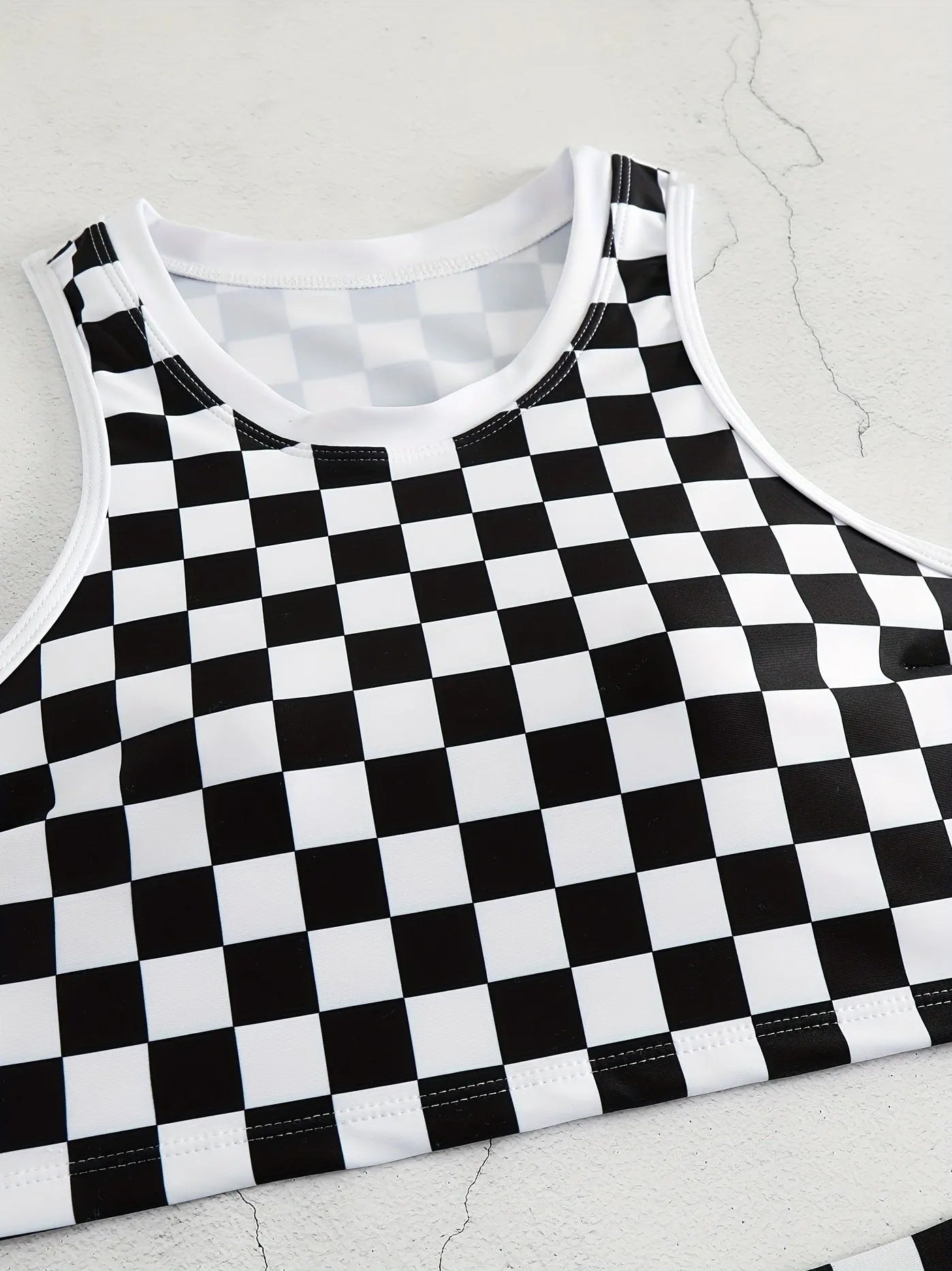 Women's backless one-piece swimsuit with black and white chessboard pattern and sporty suspender straps.