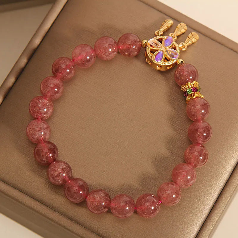 Women's strawberry quartz dream catcher ball pendant bracelet on wrist.