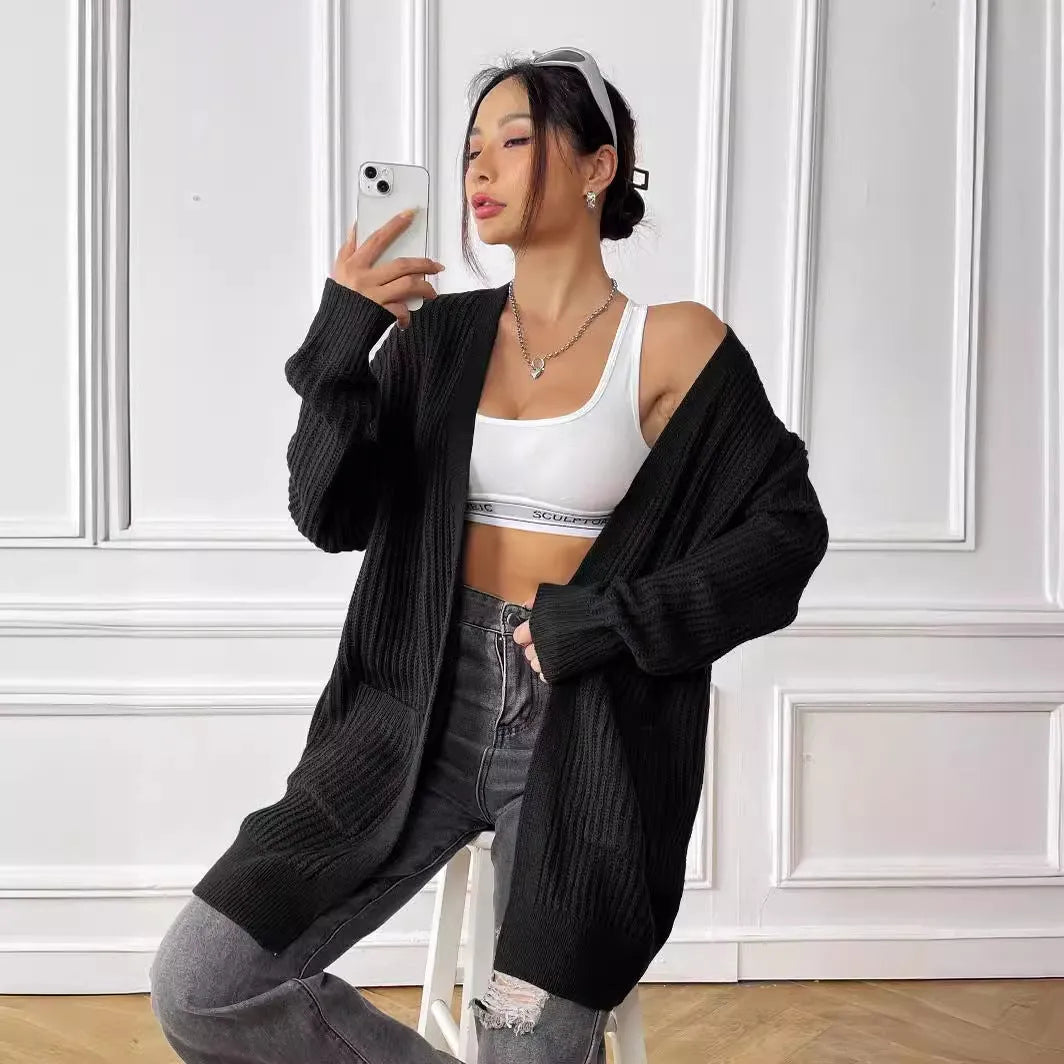 A dark green loose-fit sweater cardigan with two front pockets and long sleeves.