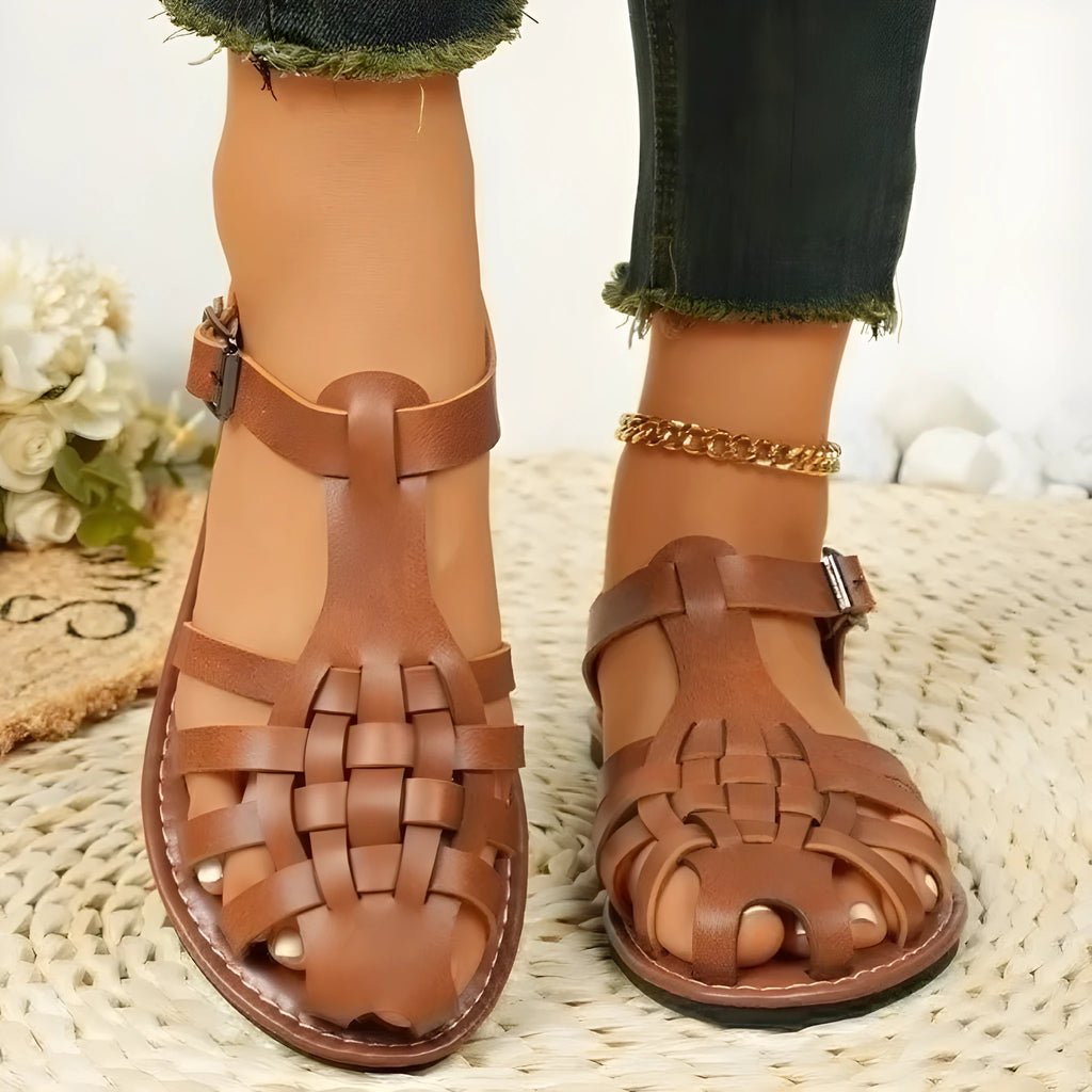 Dark brown women's Roman sandals with woven PU upper and buckle closure on a rubber sole.