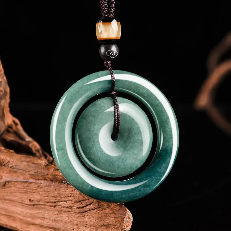 Emerald green jade pendant with carved national style design on a necklace stand