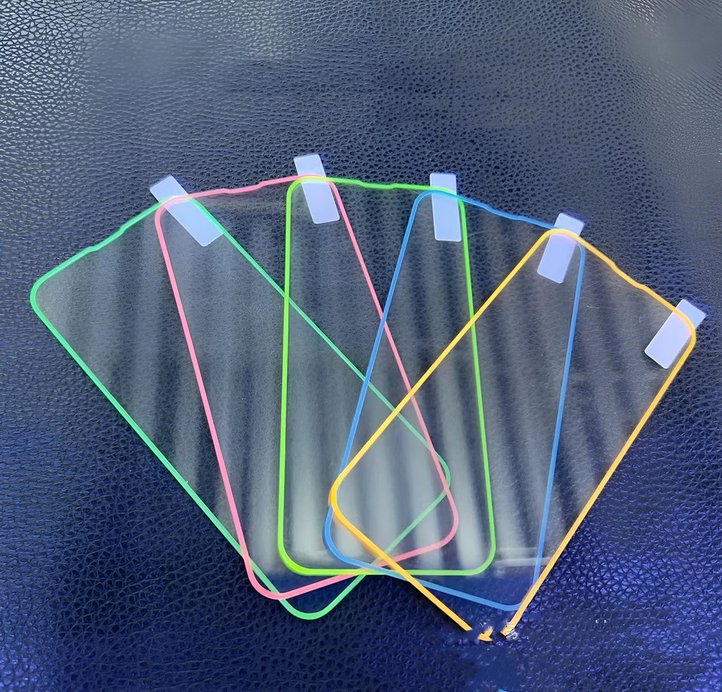 Fluorescent pink luminous tempered glass screen protector applied on an iPhone 13, glowing softly in a dark setting.