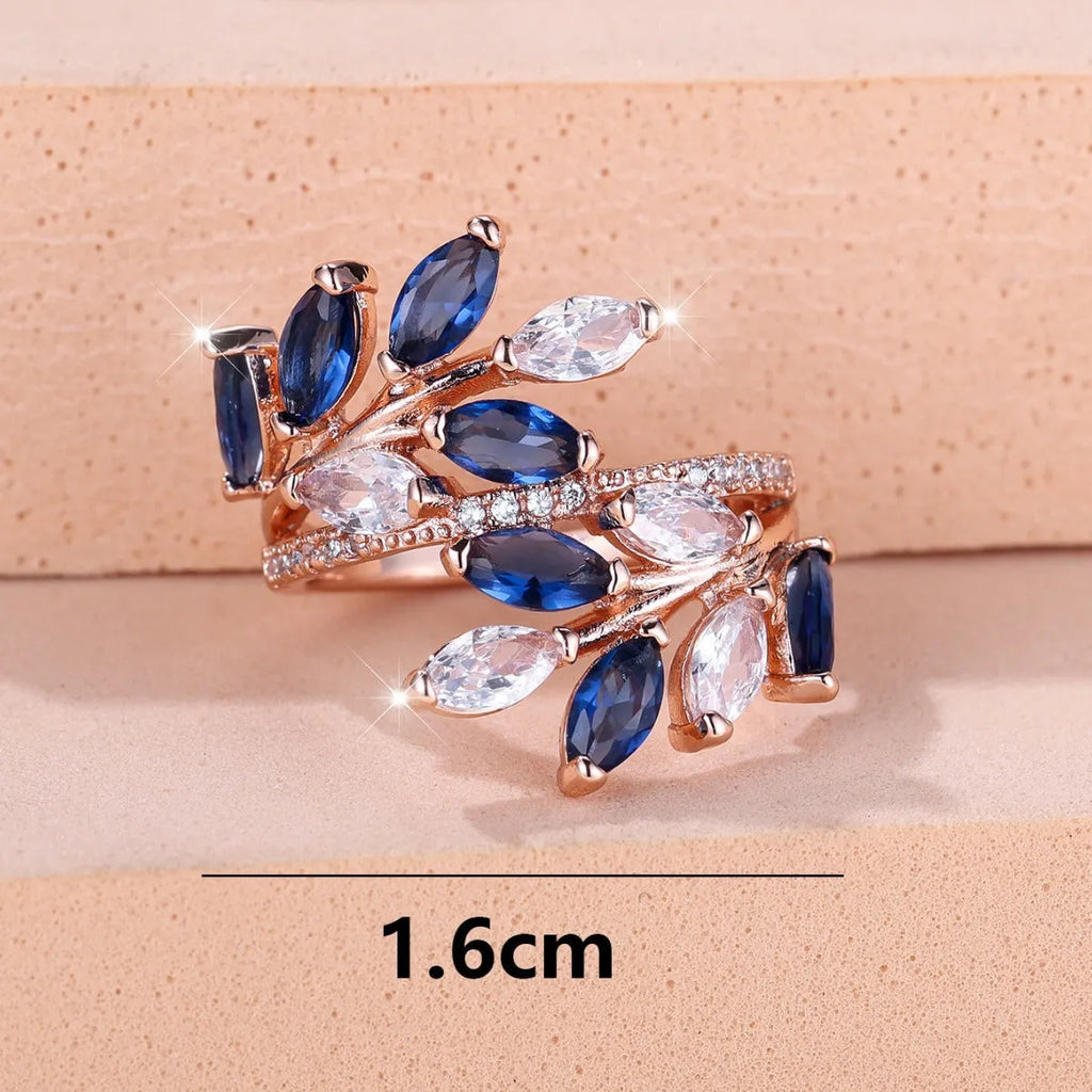Adjustable copper leaf fashion ring with a blue zircon stone on a model's hand.